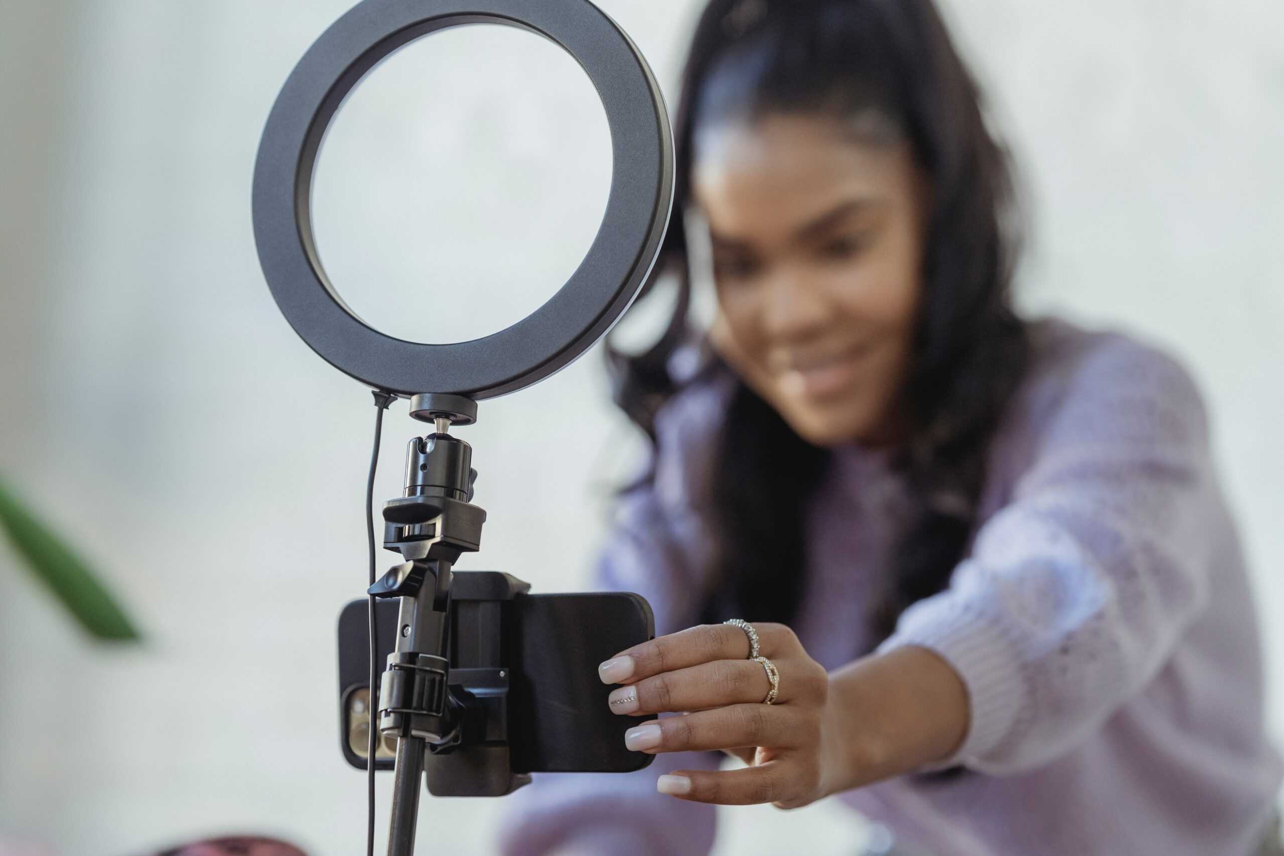 A person films themselves for social media using a ring light and a phone stand