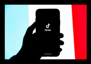 a silhouette of a hand holding a smartphone with the TikTok logo on the screen